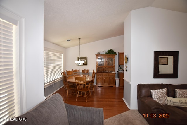 dining room featuring an inviting chandelier, lofted ceiling, wood finished floors, and a textured ceiling