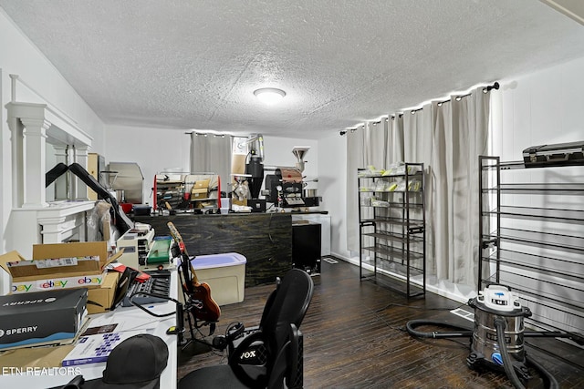 home office with a textured ceiling, decorative columns, and hardwood / wood-style flooring