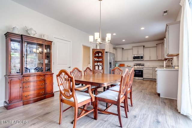 dining area with recessed lighting, visible vents, light wood-style flooring, and an inviting chandelier