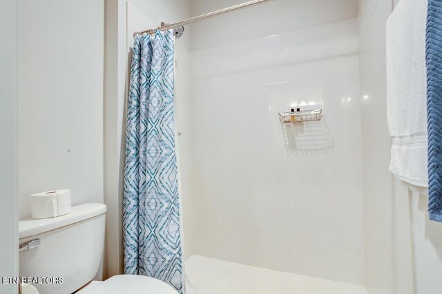 full bathroom featuring a shower with shower curtain and toilet