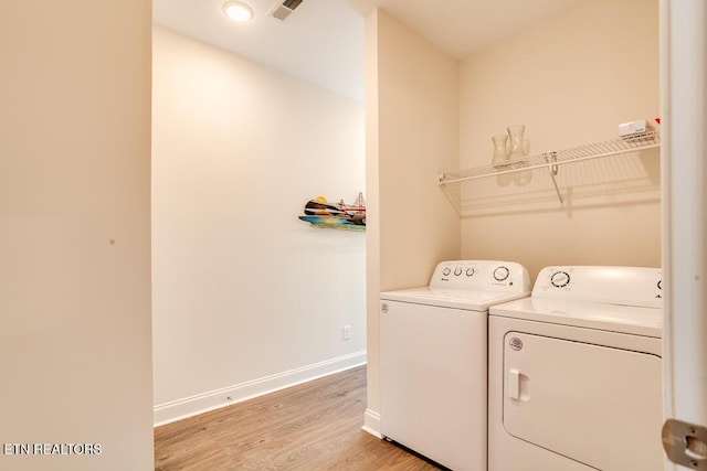 washroom featuring visible vents, washing machine and dryer, light wood-style floors, baseboards, and laundry area