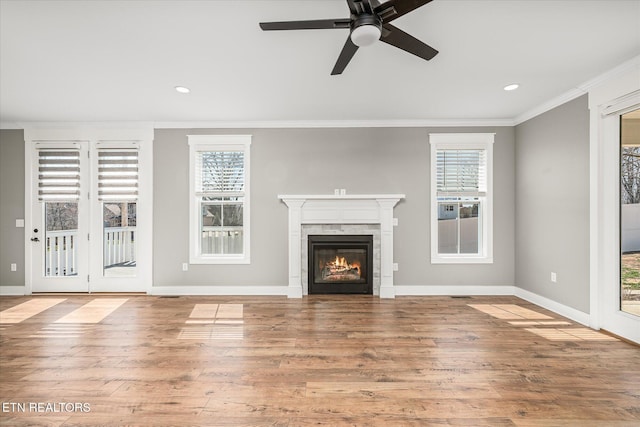 unfurnished living room with a wealth of natural light, crown molding, and wood finished floors