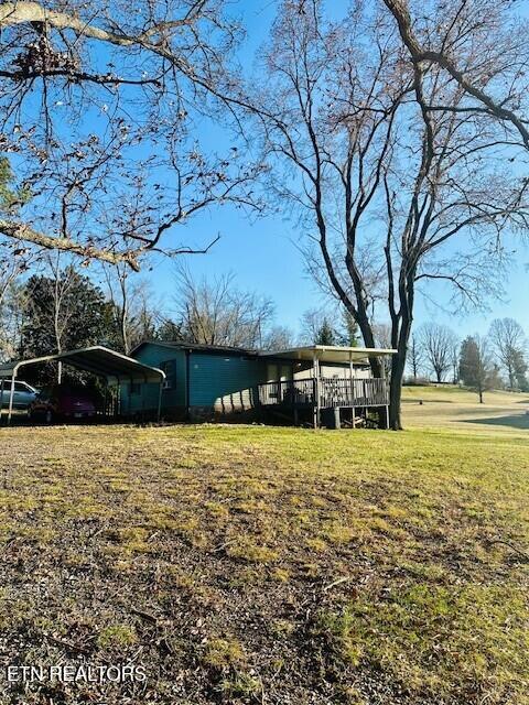 4637 Nails Creek Rd, Rockford, TN 37853 - view of front of home with a detached carport, a wooden deck, and a front lawn