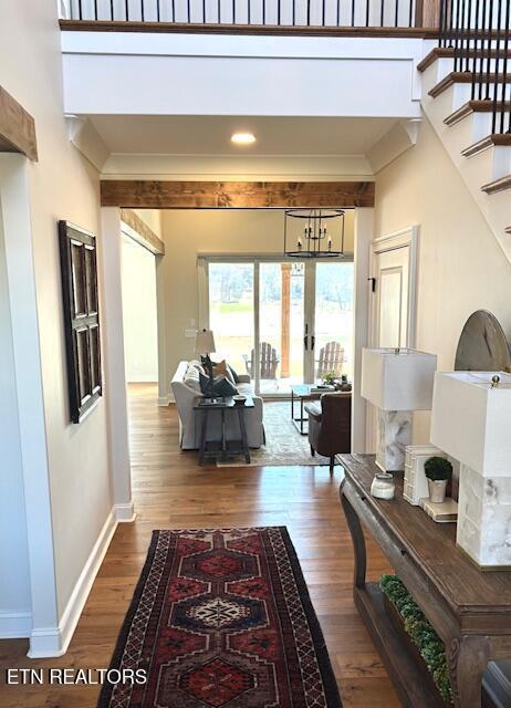 corridor featuring crown molding, stairway, wood finished floors, and baseboards