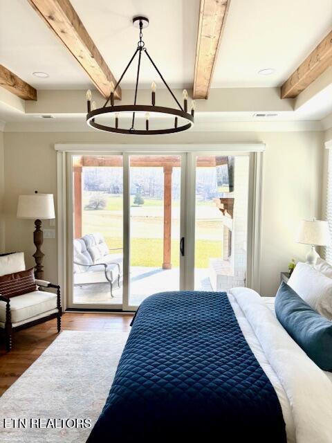 bedroom with wood finished floors, multiple windows, beam ceiling, and access to exterior