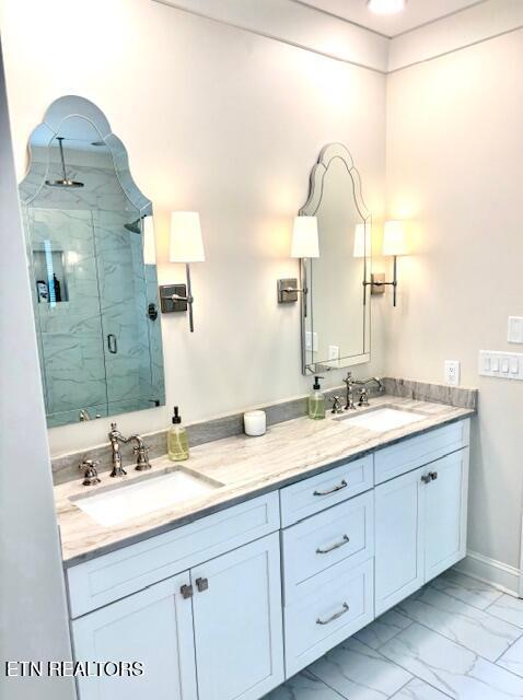 full bathroom featuring a marble finish shower, marble finish floor, double vanity, and a sink