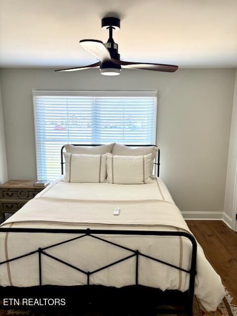 bedroom with baseboards, multiple windows, a ceiling fan, and dark wood-style flooring