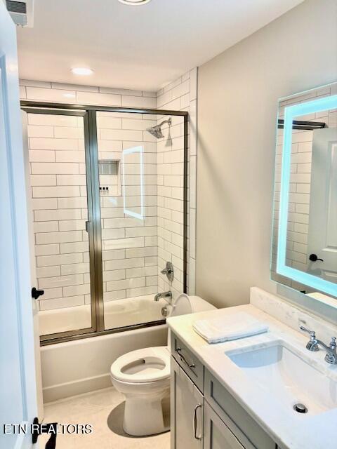 bathroom with visible vents, bath / shower combo with glass door, toilet, tile patterned floors, and vanity