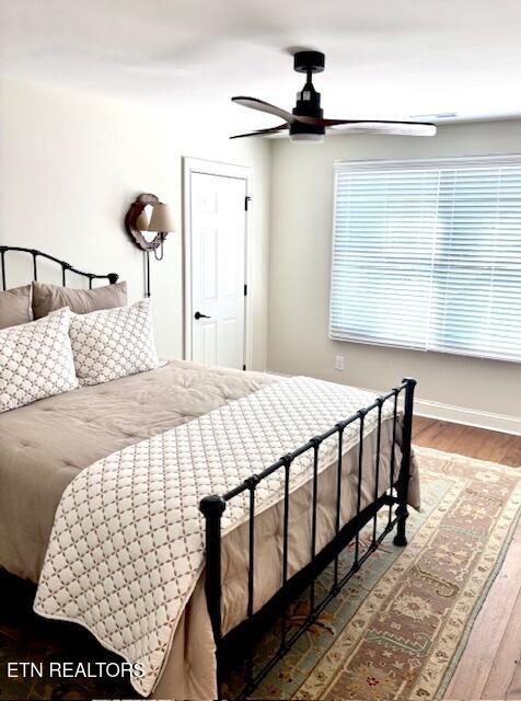 bedroom with a ceiling fan, wood finished floors, and baseboards