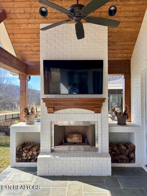 details featuring fence, an outdoor brick fireplace, and ceiling fan