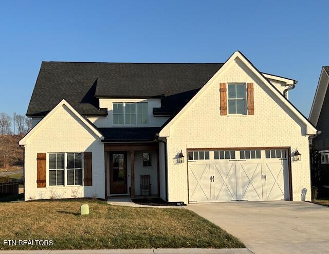 view of front of house featuring brick siding, driveway, an attached garage, and a front yard