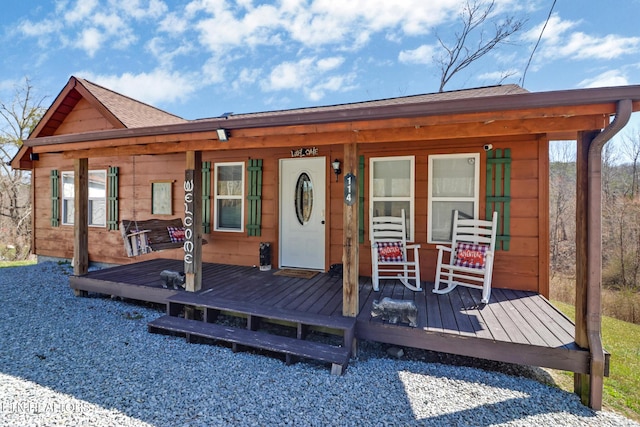 back of property featuring a porch and a shingled roof