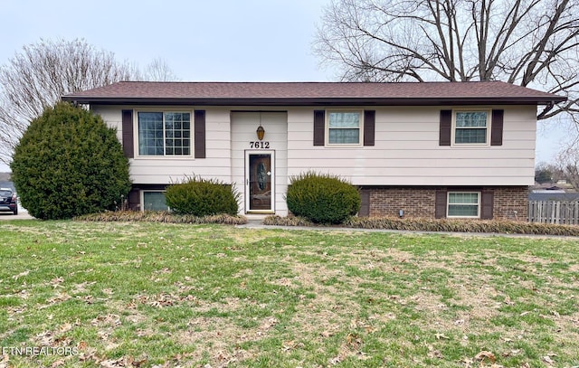 raised ranch featuring brick siding and a front lawn