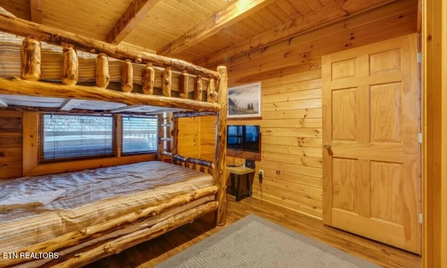 unfurnished bedroom with wood ceiling, wooden walls, wood finished floors, and beamed ceiling