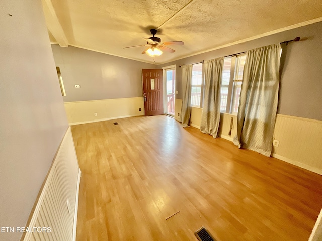 spare room with visible vents, a wainscoted wall, ceiling fan, a textured ceiling, and light wood-type flooring