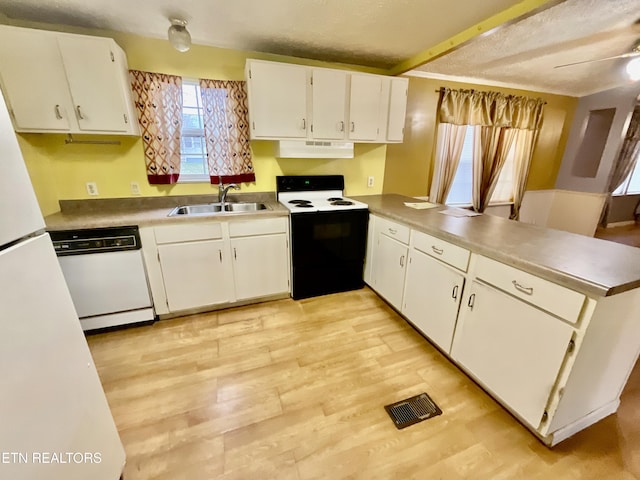 kitchen featuring visible vents, under cabinet range hood, a peninsula, white appliances, and a sink