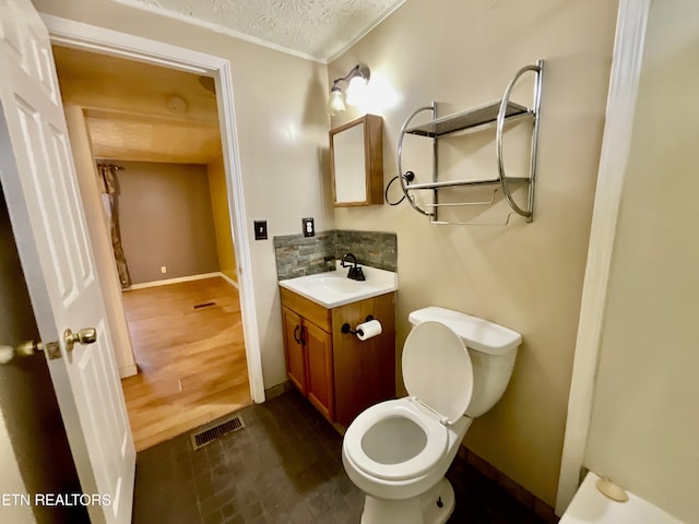 bathroom with vanity, visible vents, decorative backsplash, a textured ceiling, and toilet