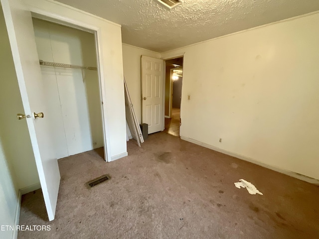 unfurnished bedroom featuring visible vents, a textured ceiling, a closet, carpet floors, and baseboards