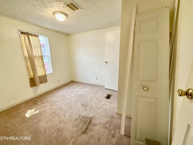 carpeted empty room with visible vents, a textured ceiling, and baseboards