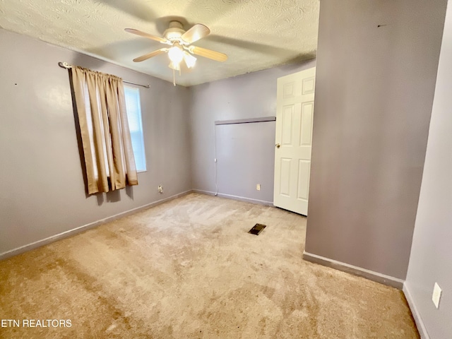 unfurnished bedroom with carpet, baseboards, visible vents, ceiling fan, and a textured ceiling