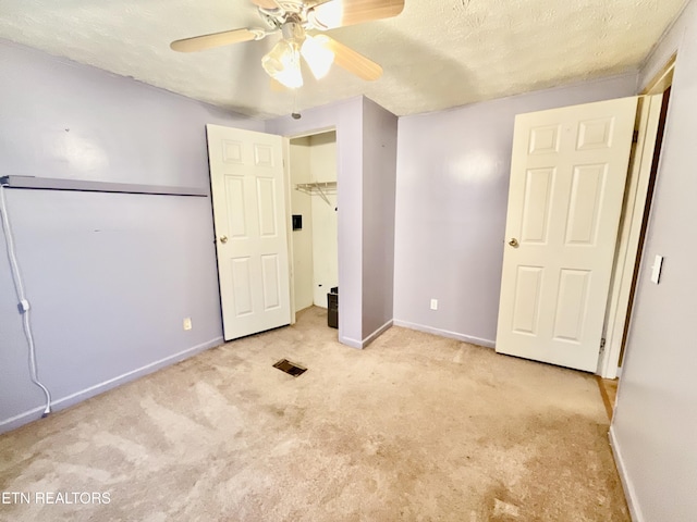 unfurnished bedroom featuring a ceiling fan, visible vents, baseboards, a textured ceiling, and light colored carpet