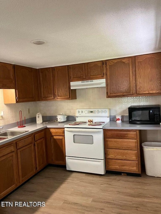 kitchen with backsplash, black microwave, under cabinet range hood, light wood-type flooring, and white electric stove