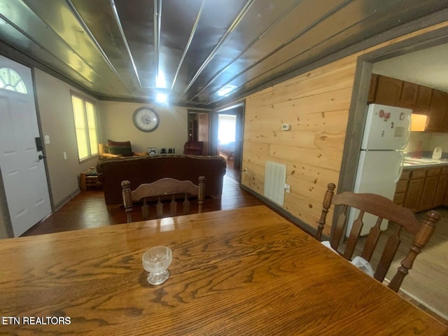 dining area with wooden walls, radiator heating unit, and dark wood-style floors