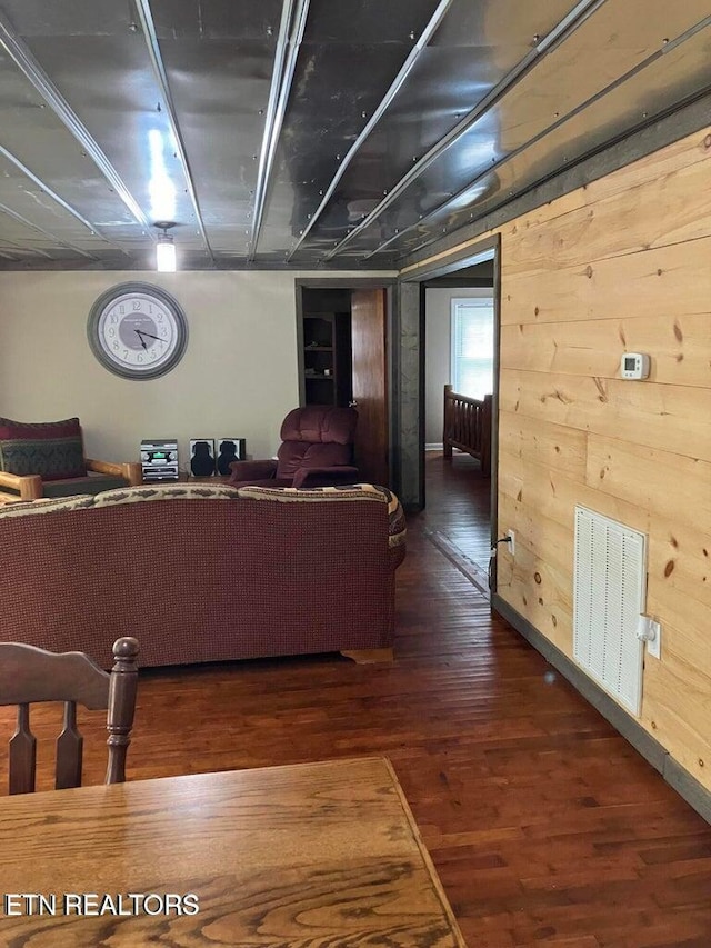 unfurnished living room featuring wooden walls, wood finished floors, and visible vents