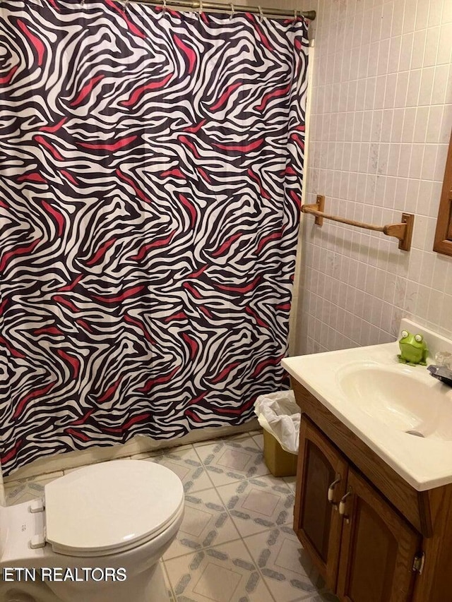 bathroom with vanity, tile walls, and toilet