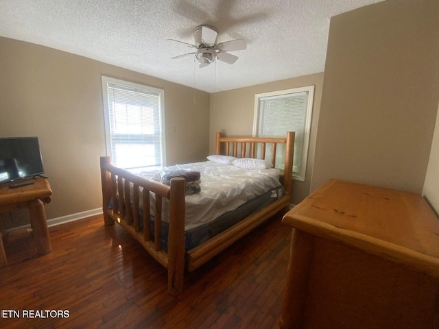 bedroom with dark wood-type flooring, a ceiling fan, baseboards, and a textured ceiling