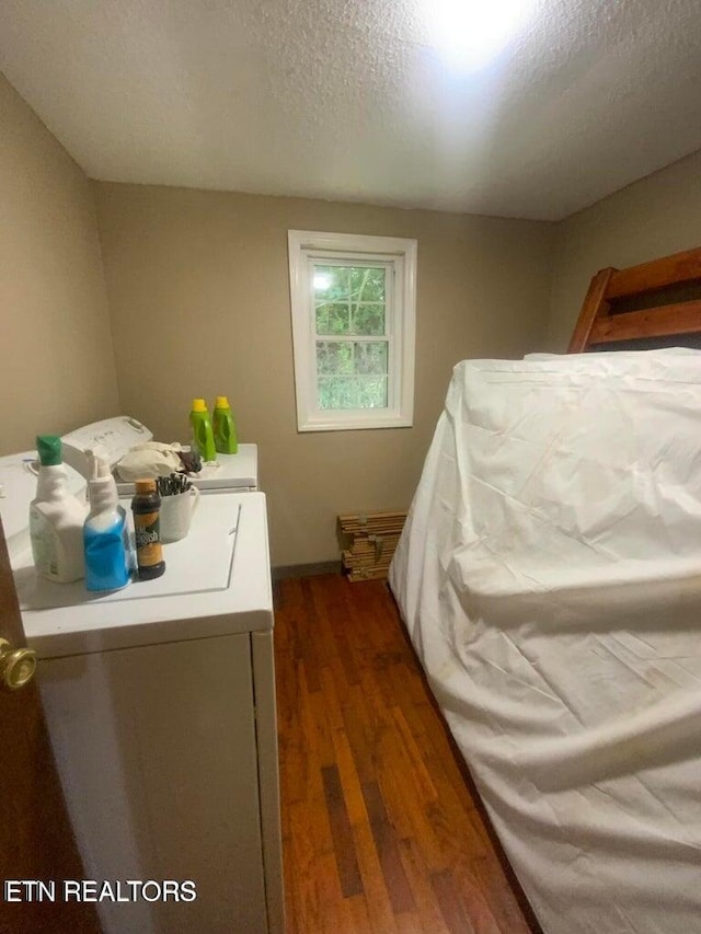 clothes washing area with washer and dryer, a textured ceiling, dark wood finished floors, and laundry area