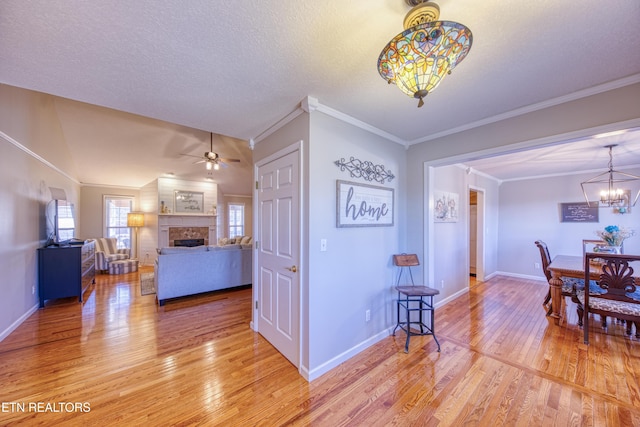 interior space featuring light wood-style flooring, a fireplace, crown molding, and baseboards