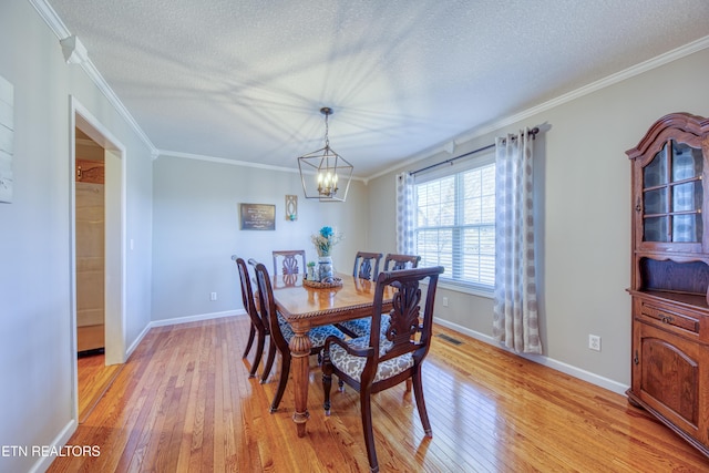 dining room with baseboards, light wood-style floors, ornamental molding, and a textured ceiling