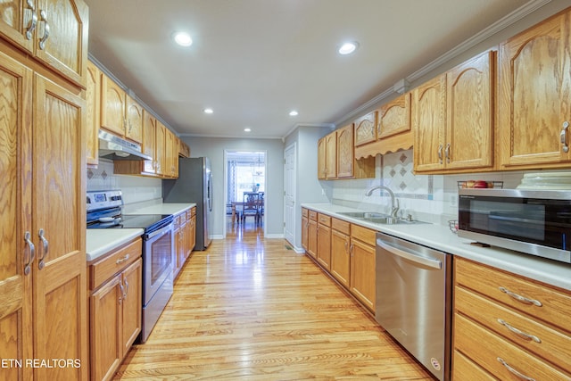 kitchen with light wood-style flooring, a sink, light countertops, under cabinet range hood, and appliances with stainless steel finishes