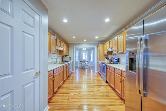 kitchen featuring a sink, appliances with stainless steel finishes, ornamental molding, and light countertops