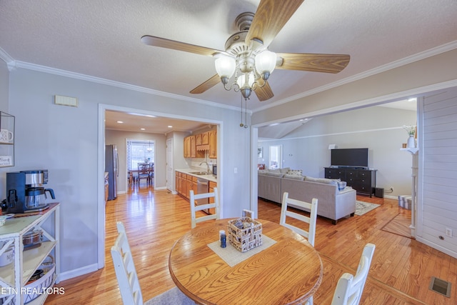 dining space featuring crown molding, light wood-style floors, visible vents, and a textured ceiling