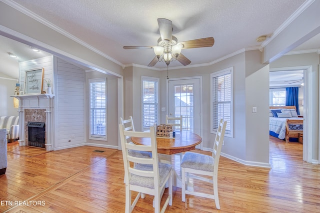 dining space with light wood-style flooring, a fireplace, and ornamental molding