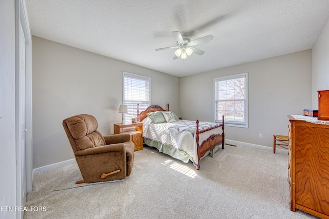 bedroom with baseboards, multiple windows, light colored carpet, and a textured ceiling