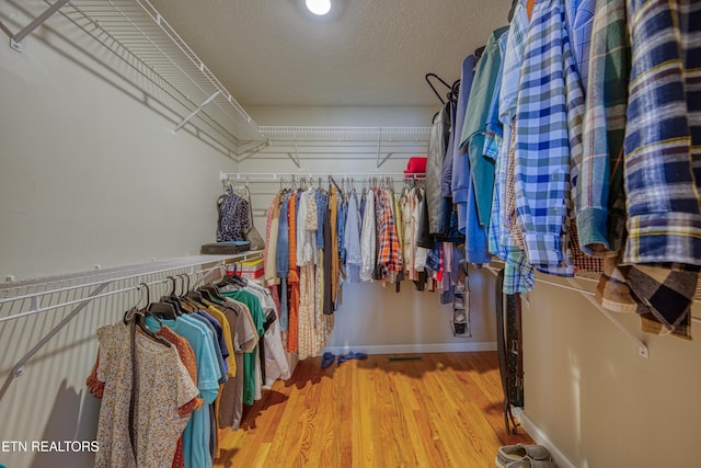 walk in closet with wood finished floors