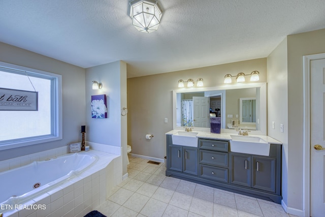 full bath featuring a textured ceiling, double vanity, a whirlpool tub, and a sink