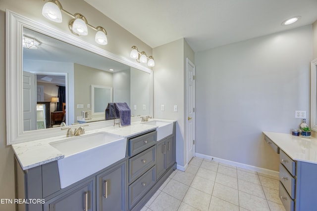 bathroom with a sink, baseboards, double vanity, and tile patterned flooring