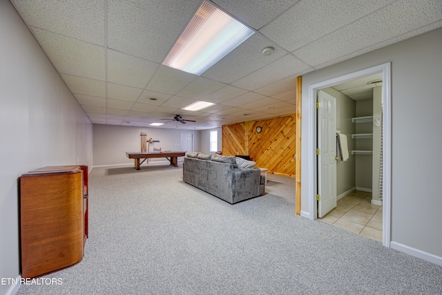 unfurnished living room featuring wooden walls, carpet flooring, and a drop ceiling