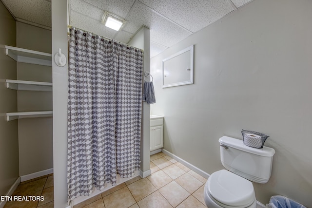 bathroom with a shower with shower curtain, baseboards, a paneled ceiling, tile patterned floors, and toilet