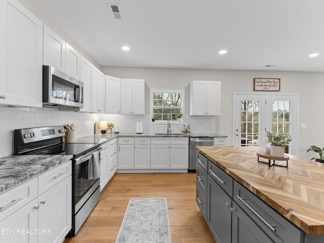 kitchen featuring gray cabinets, white cabinetry, stainless steel appliances, and wood counters