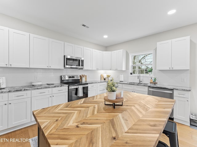 kitchen with white cabinets, visible vents, appliances with stainless steel finishes, and a sink