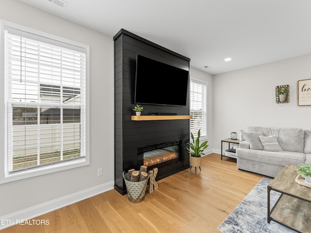 living room featuring recessed lighting, baseboards, light wood-style flooring, and a fireplace