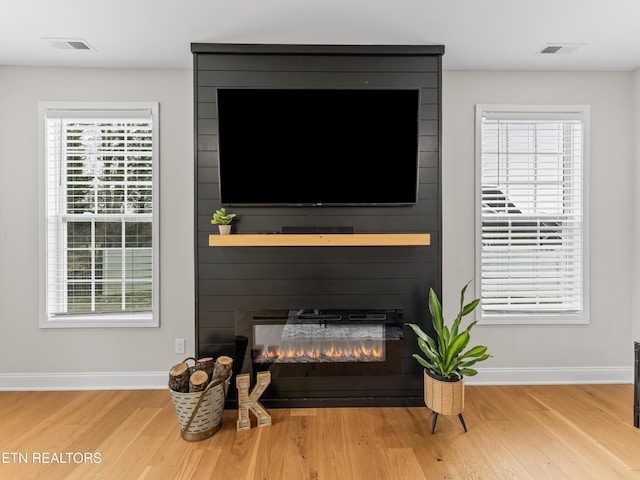 details featuring wood finished floors, a fireplace, baseboards, and visible vents