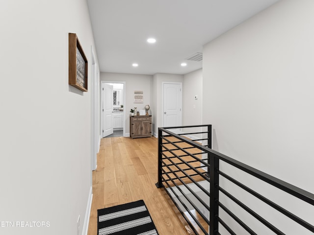 hall with visible vents, baseboards, an upstairs landing, light wood-style flooring, and recessed lighting