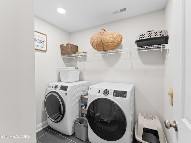 clothes washing area with laundry area, washing machine and dryer, visible vents, and dark tile patterned flooring