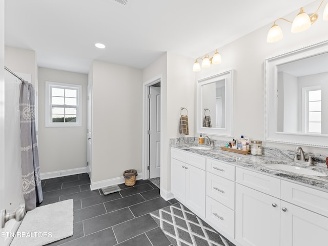 full bath with tile patterned flooring, double vanity, baseboards, and a sink